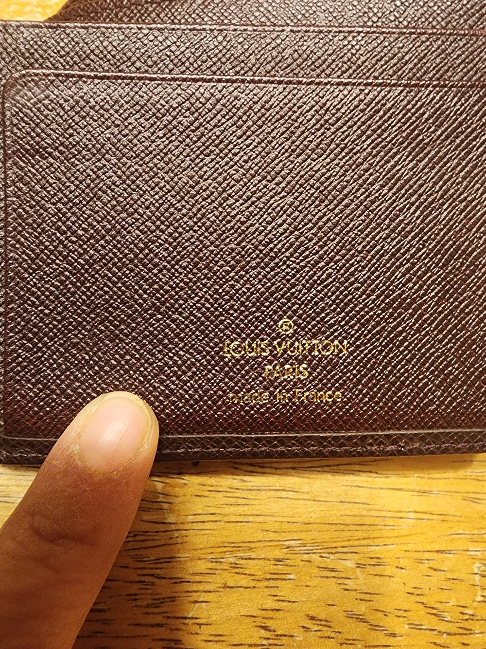 burgandy Louis Vuitton Taiga leather bifold wallet featuring a debossed LV